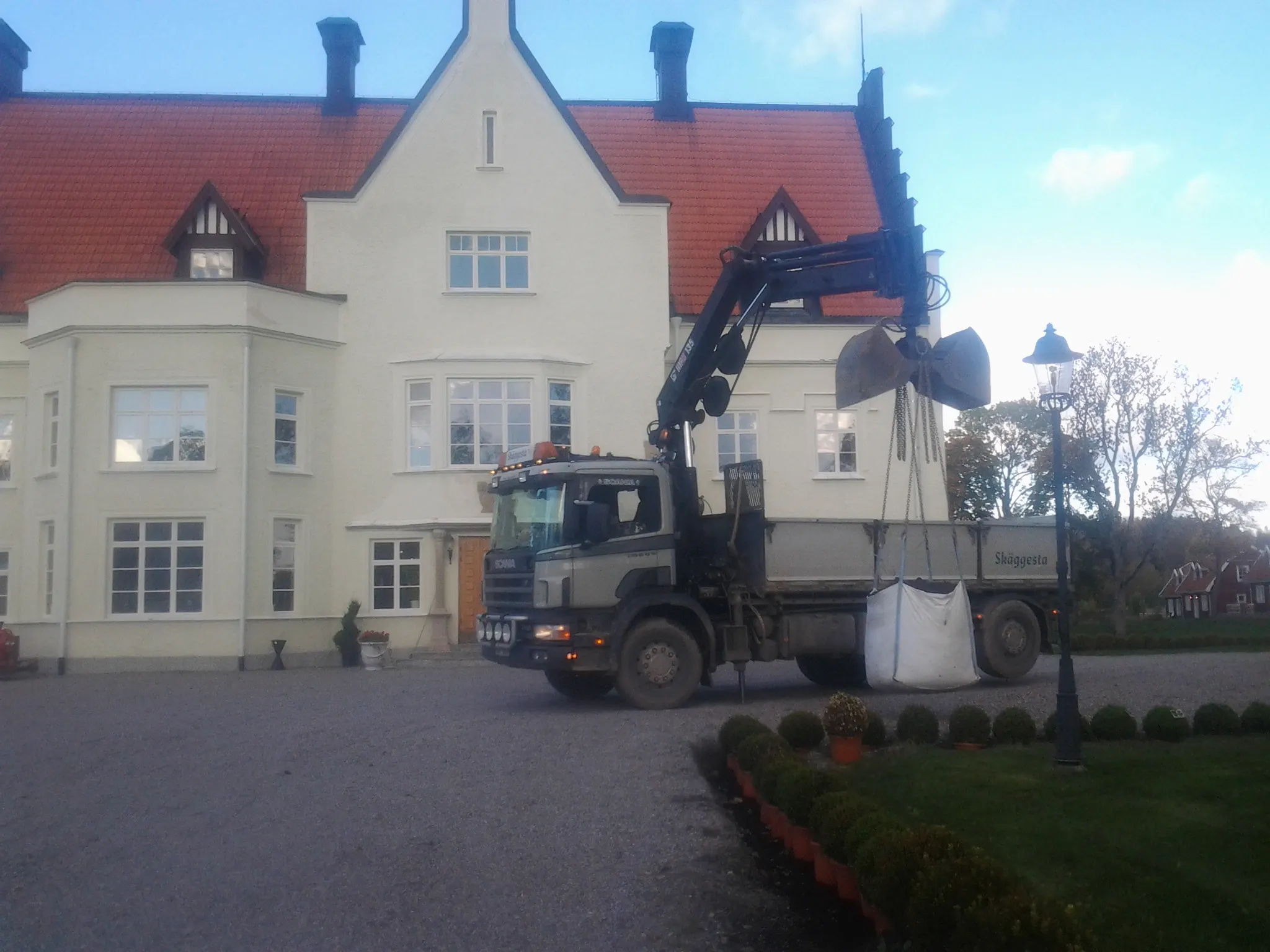 Lastbil med kran lastar av material vid en herrgård